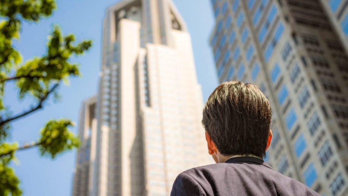 昼間にオフィス街を歩いているスーツを着た男性の後ろ姿