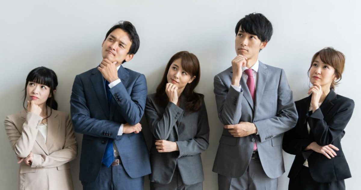 首をかしげるスーツを着た5人の男女