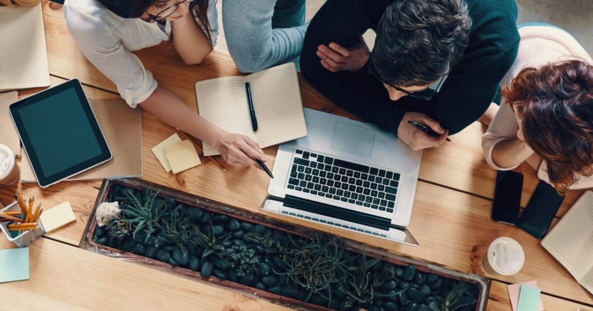 パソコンとメモ帳を見ながら話し合う男女