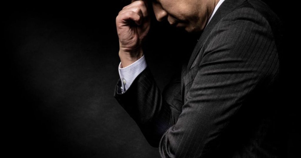 頭を抱えるスーツ姿の男性