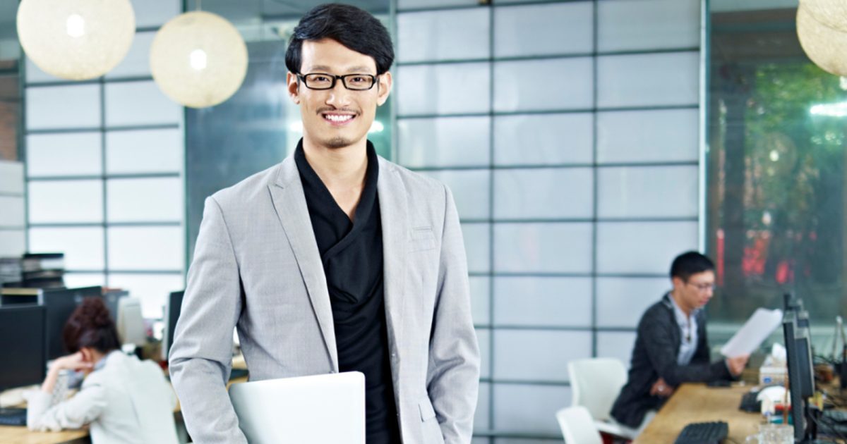 パソコンを手に持っているスーツを着た男性