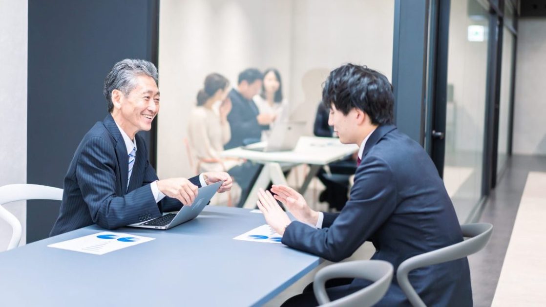 会議室で向かい合って話し合う二人のビジネスマン