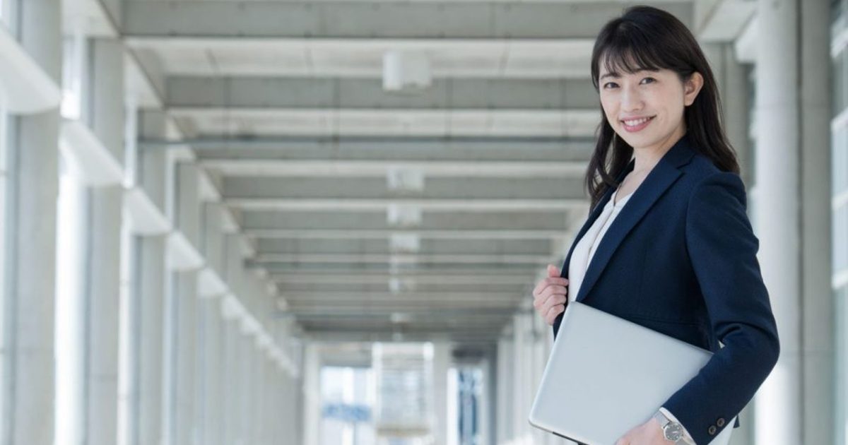 パソコンを持ったスーツ姿の女性が振り向く様子