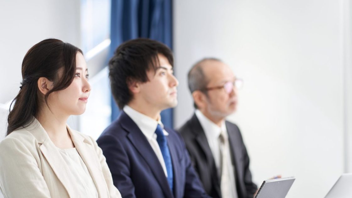 話を聞いている3人のスーツ姿の男女