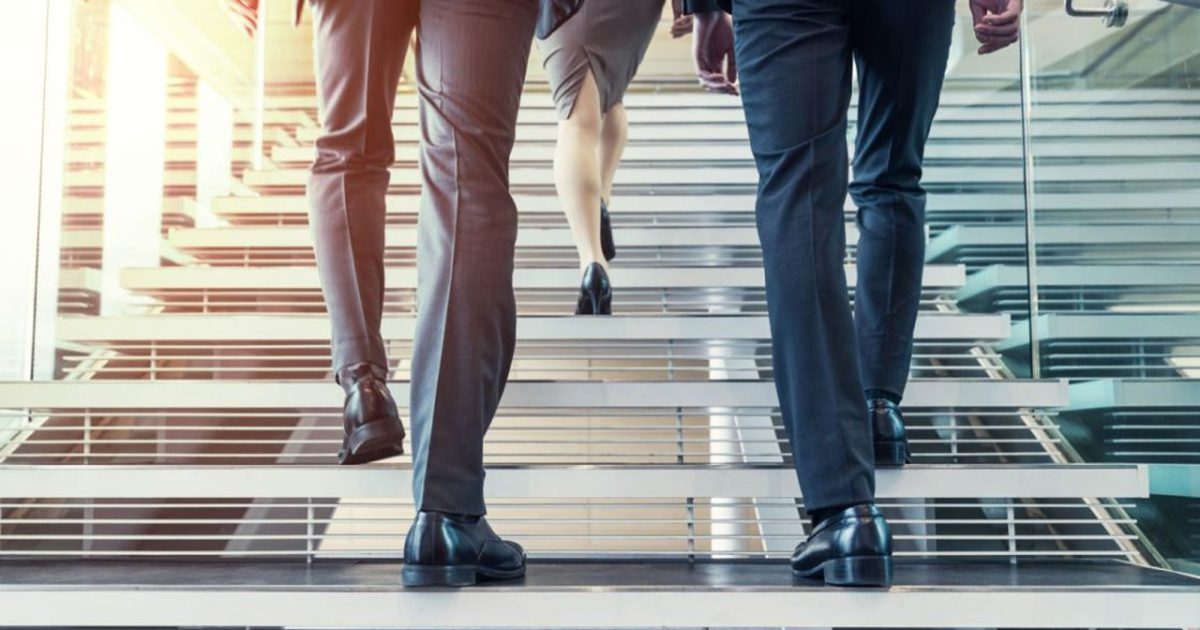 階段を上るスーツを着た男女