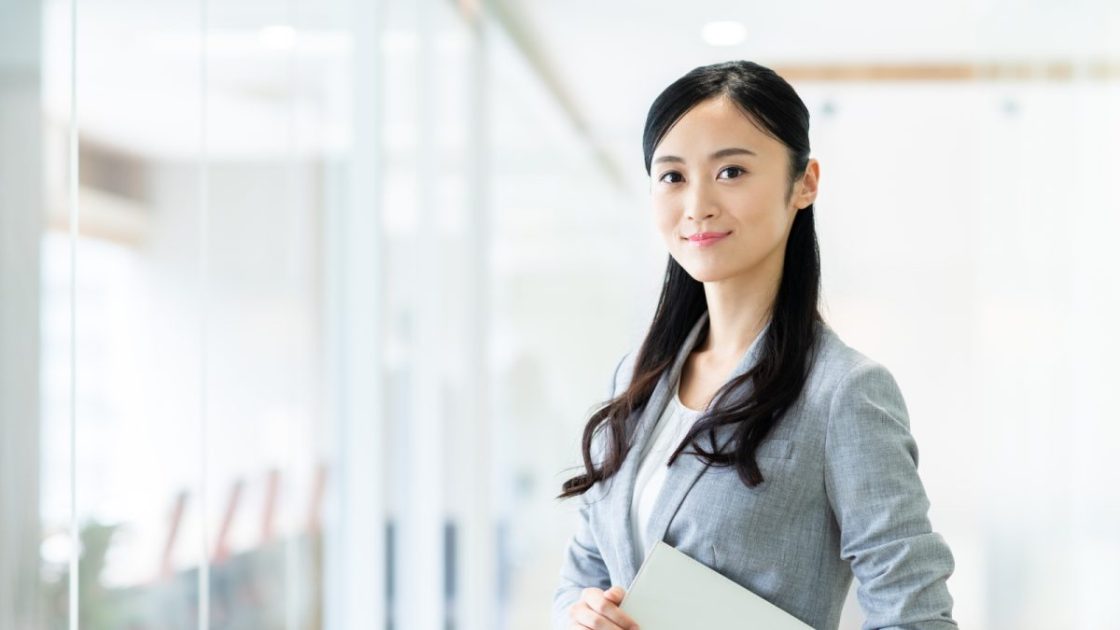 オフィスに立っているグレーのスーツを着た女性