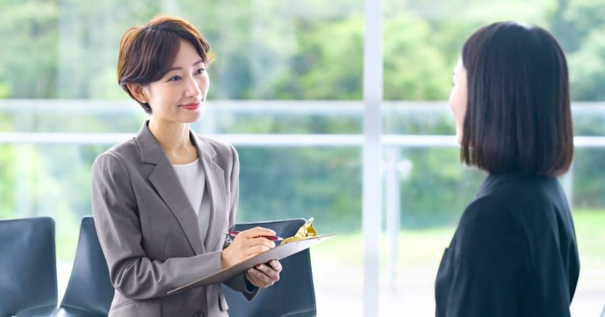 立ったまま話すスーツ姿の女性二人
