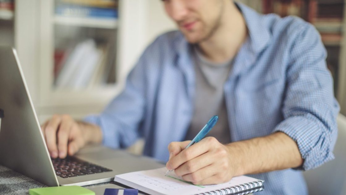 パソコンを見ながらメモを取る男性