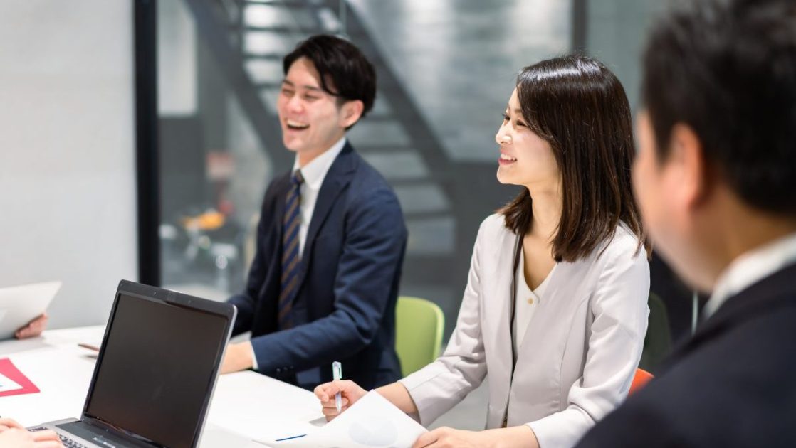 手元に資料を置いて話すスーツ姿の男女