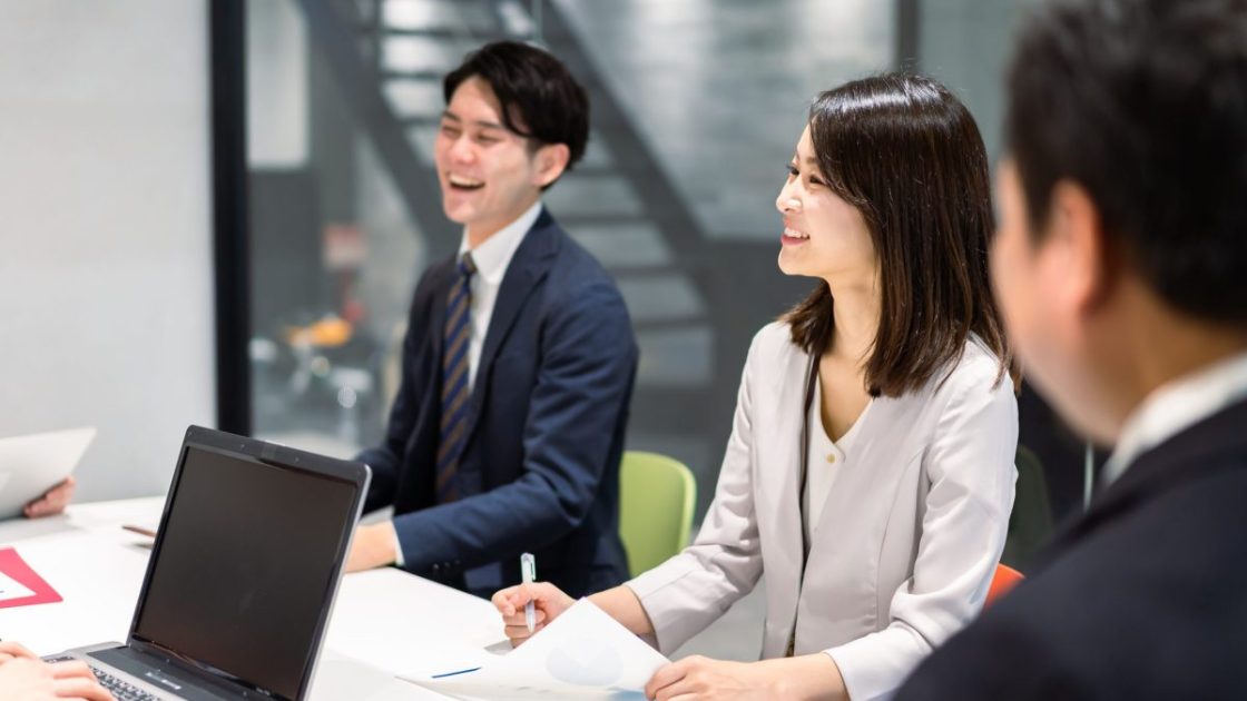 手元に資料を置いて話すスーツ姿の男女