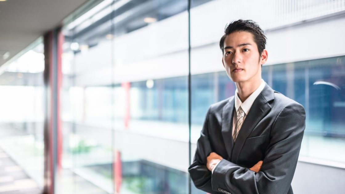 腕を組んで立っているスーツ姿の男性