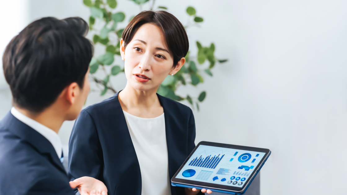 タブレットに資料を表示して話すスーツ姿の女性