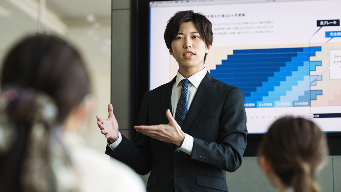 モニターに資料を映してプレゼンするビジネスマン