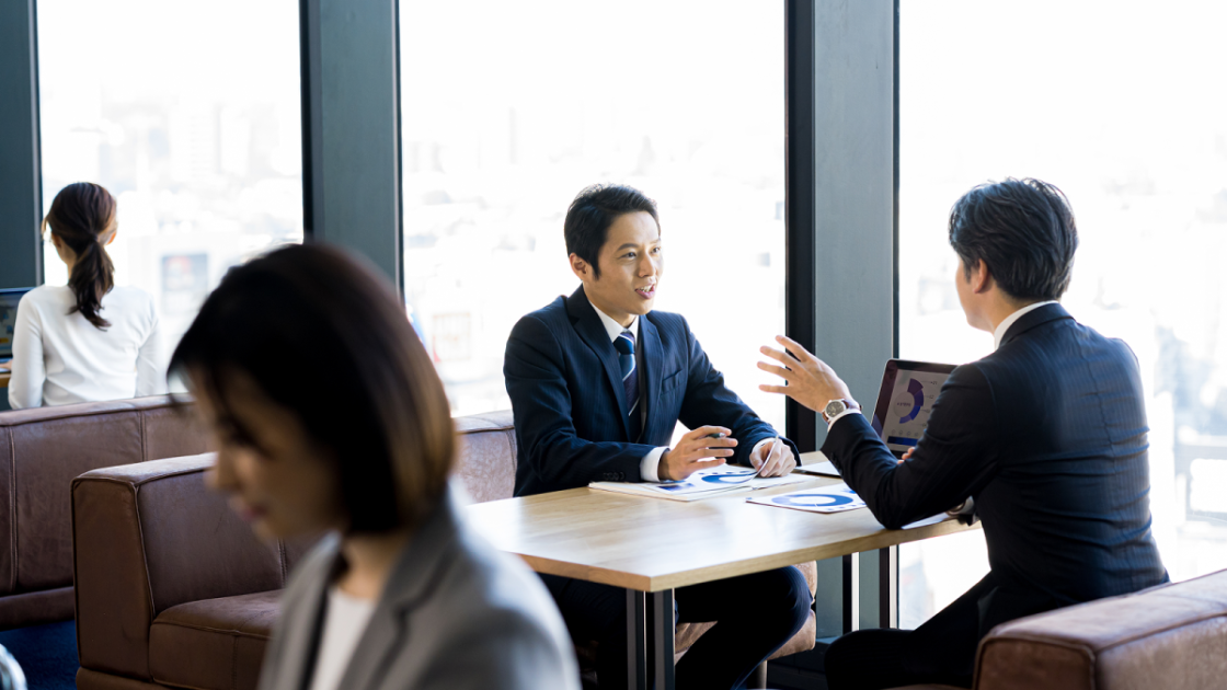 オフィスのオープンスペースで話し合う男性二人