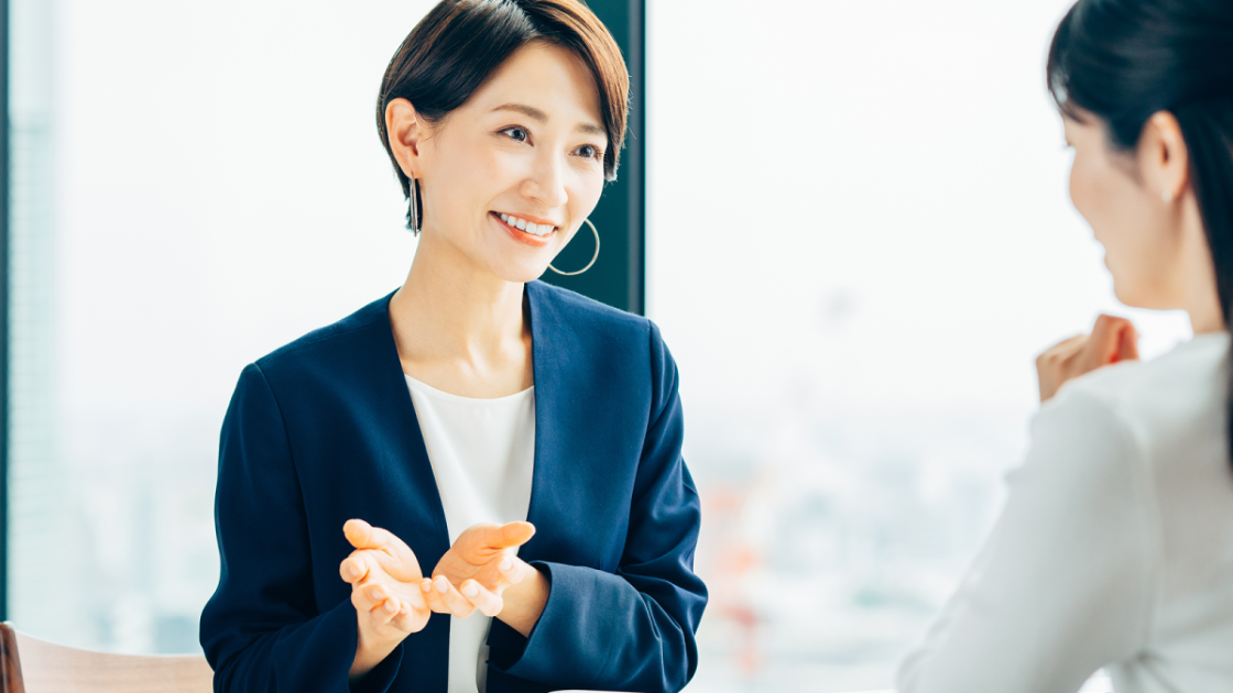 ジェスチャーをしながら話すスーツ姿の女性