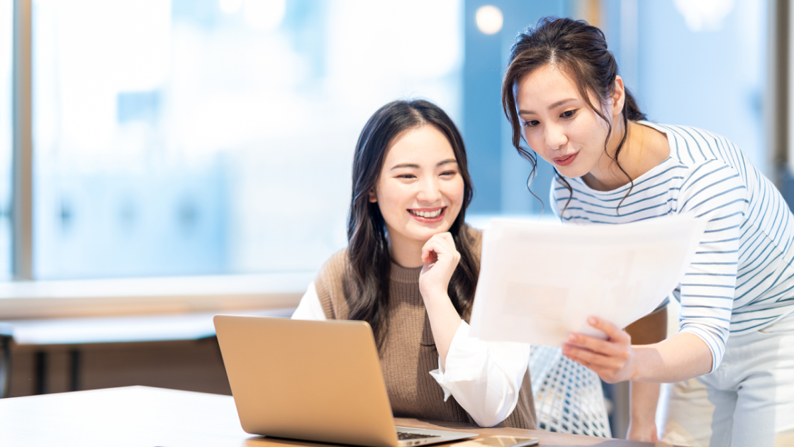 印刷した資料を見ながら話す二人の女性