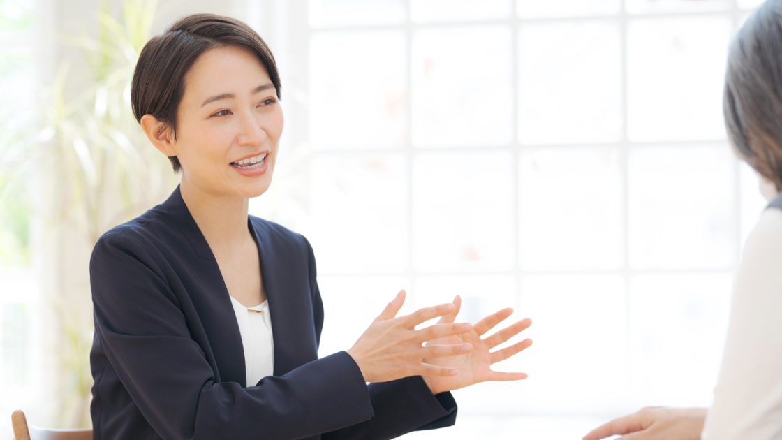 ジェスチャーをしながら話すスーツ姿の女性
