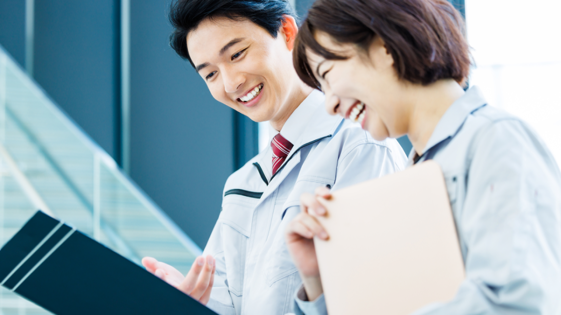 作業着を着た男女が笑顔で話している様子