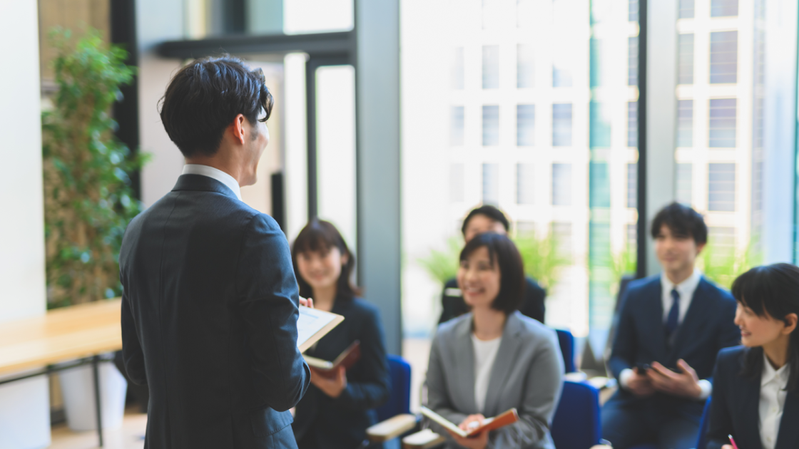 スーツを着た社会人の前で講義をする男性