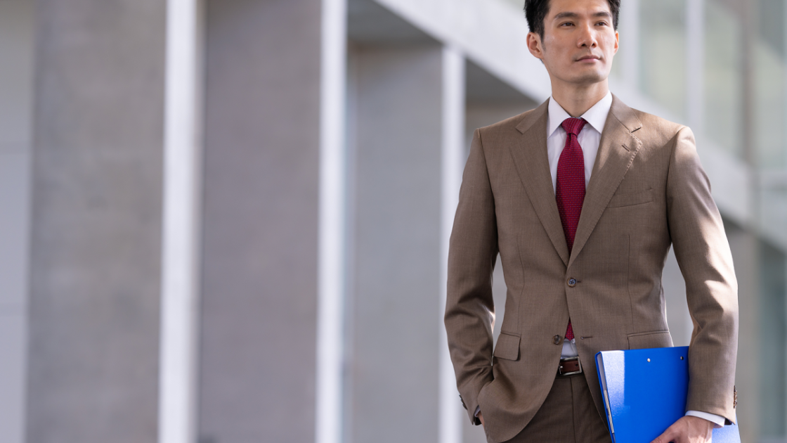 ファイルを片手に持って立っているスーツ姿の男性
