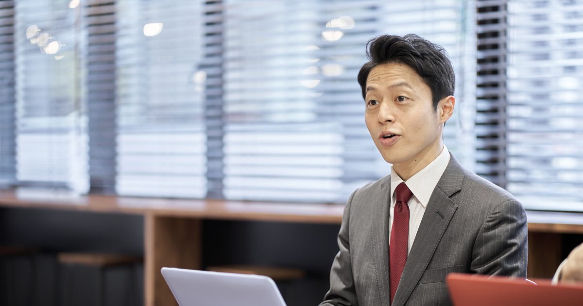 ノートパソコンの前に座って話すビジネスマン