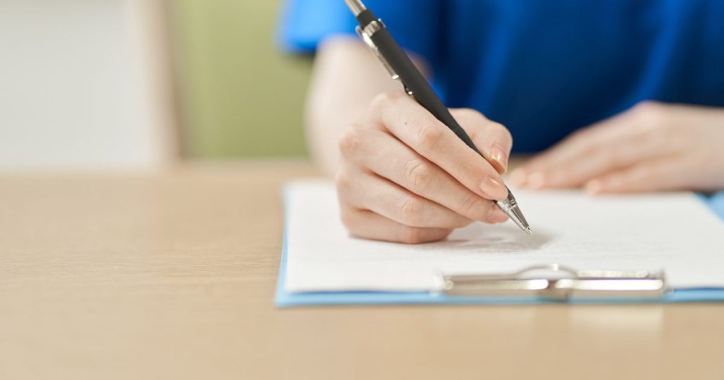 バインダーで挟んだ紙にメモを書く女性