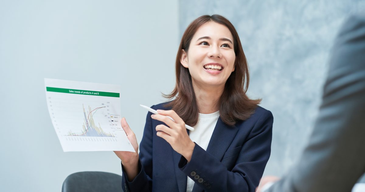 資料を指さしながら話すスーツ姿の女性