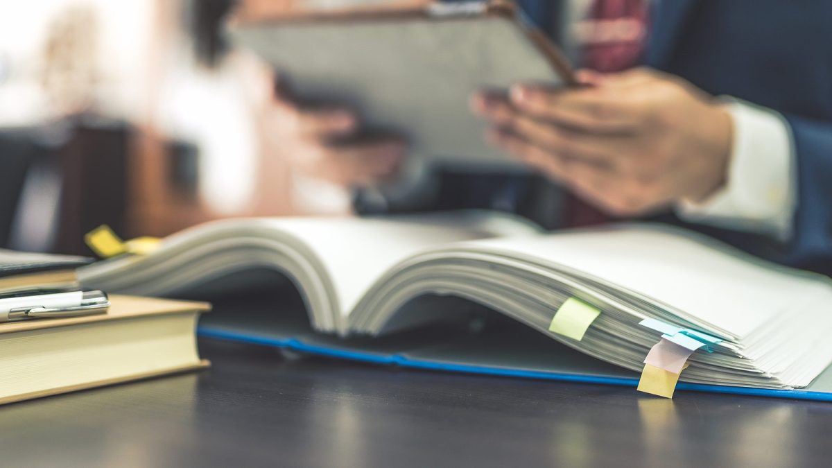 付箋を貼った紙の資料を読む男性