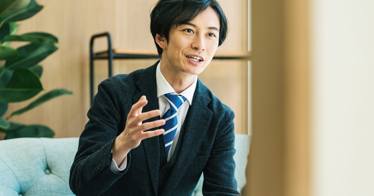右手を動かしながら話すスーツ姿の男性