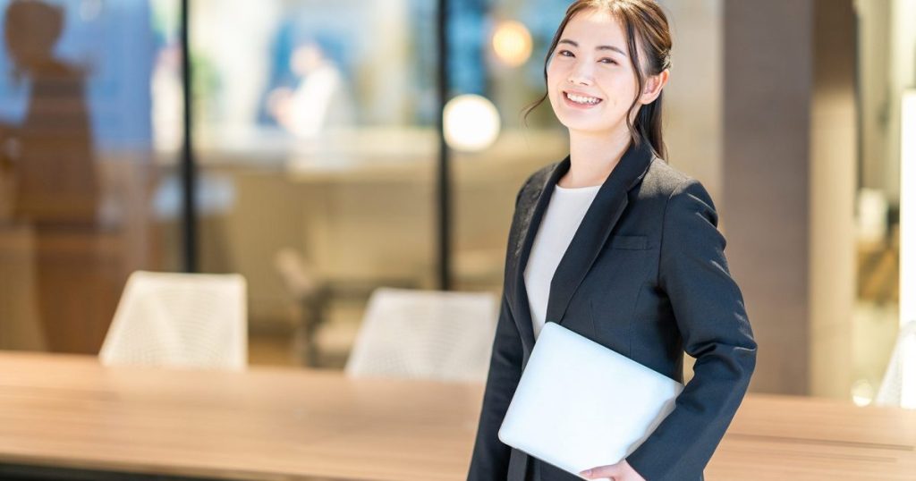 パソコンを片手に持っている笑顔の女性