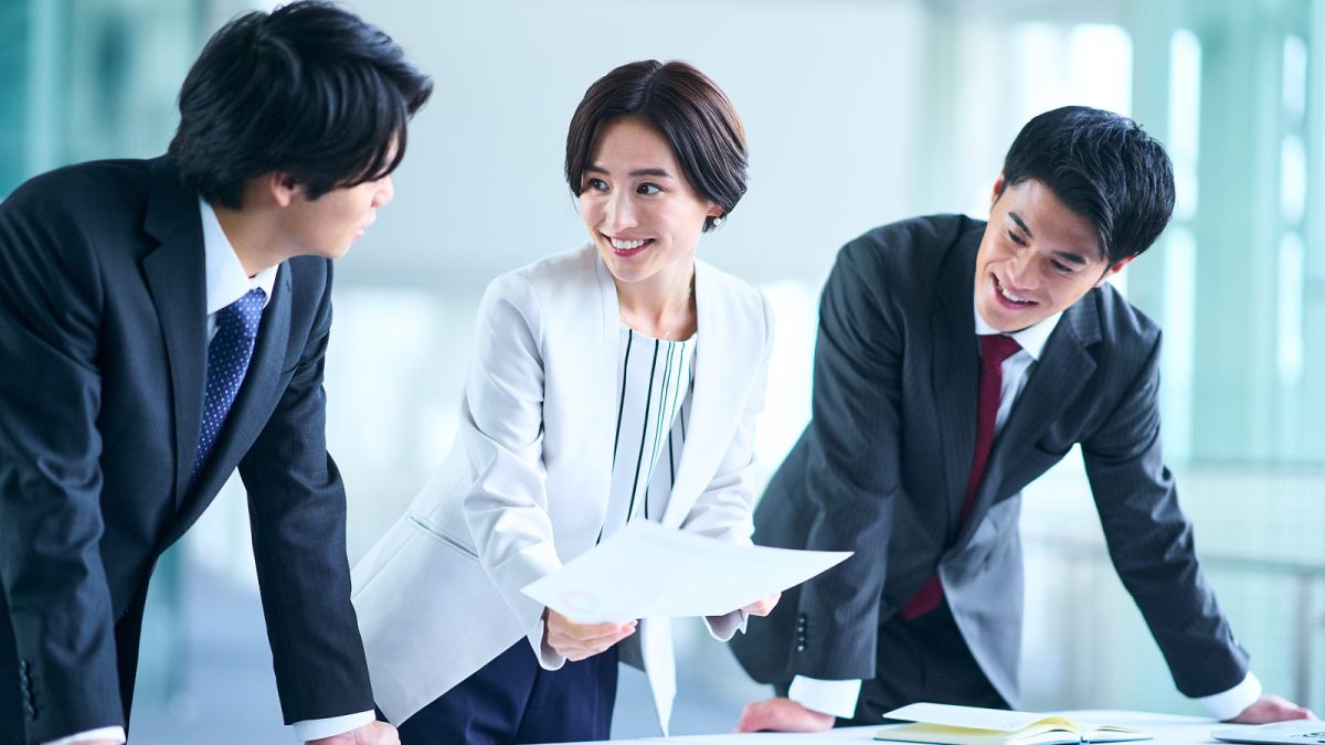 オフィスで紙の資料を見ながら話す男女