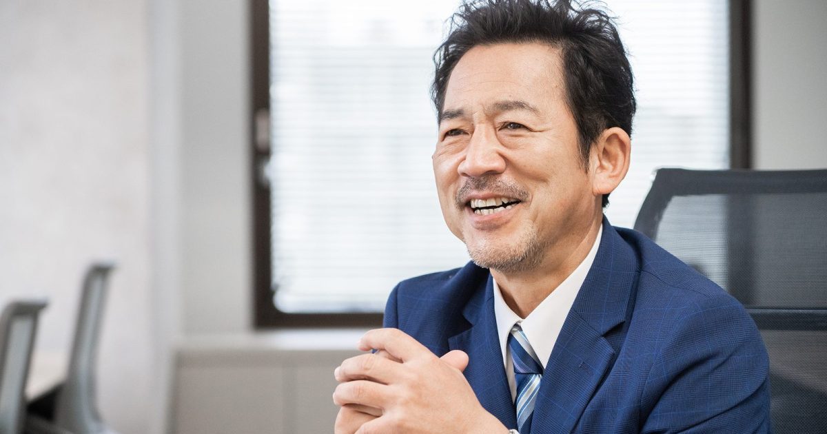 指を組んで座っている中年のビジネスマン
