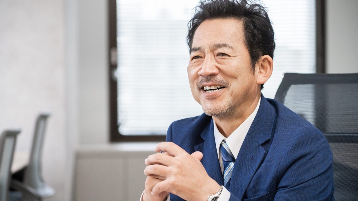 指を組んで座っている中年のビジネスマン