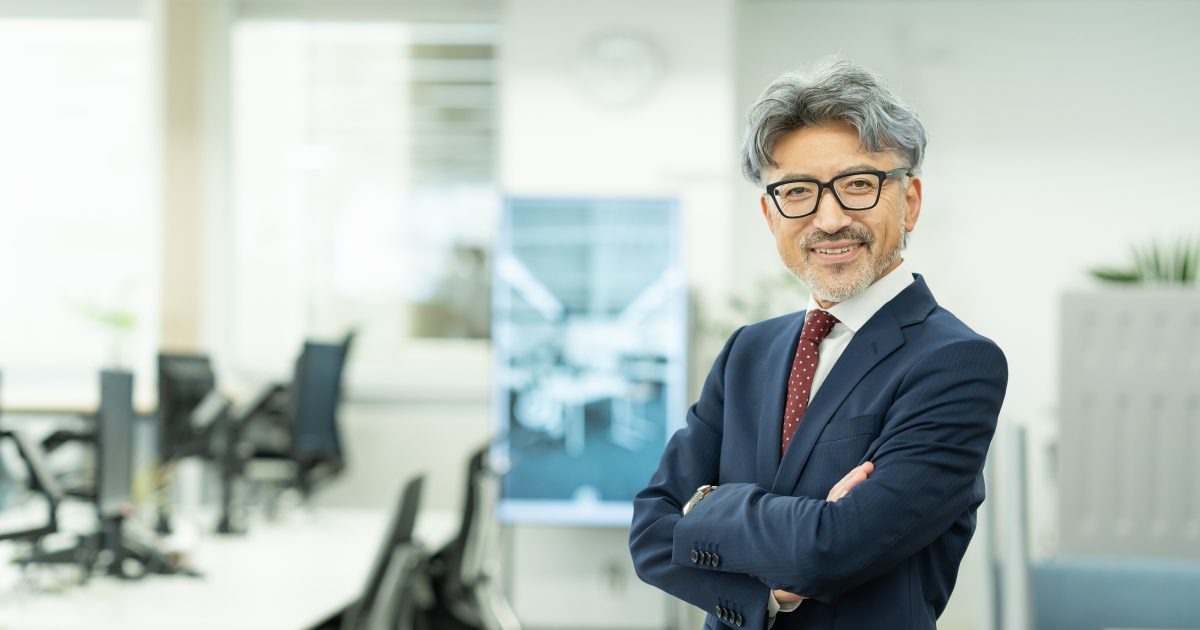 腕を組んでオフィスに立つ中年男性