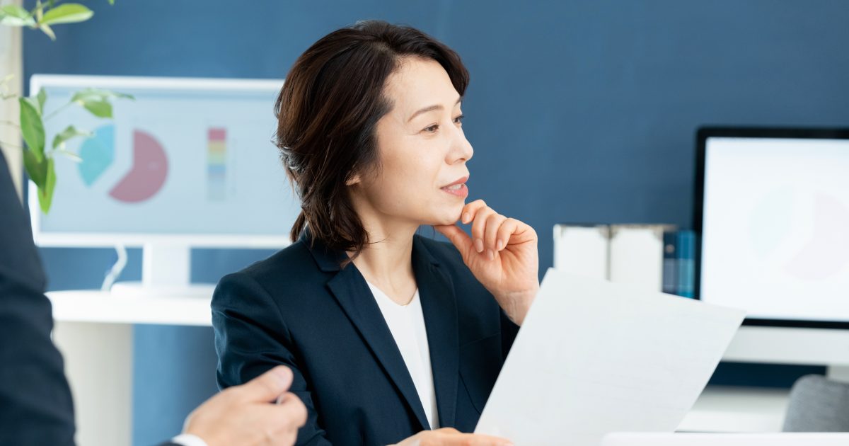 顎に手を当てるスーツ姿の女性