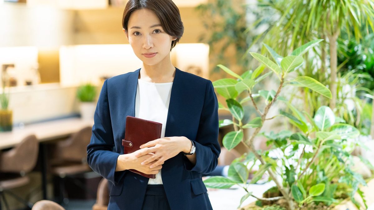 メモ帳を持って立つスーツ姿の女性