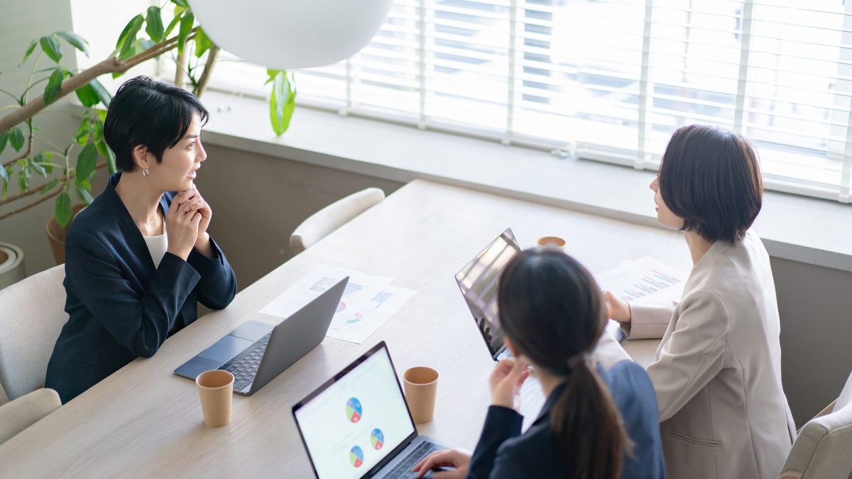 自然光の入る会議室で話し合う３人の女性
