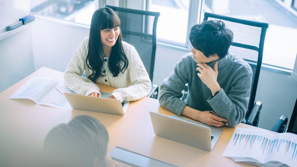 A man and woman talking while operating a laptop in the office