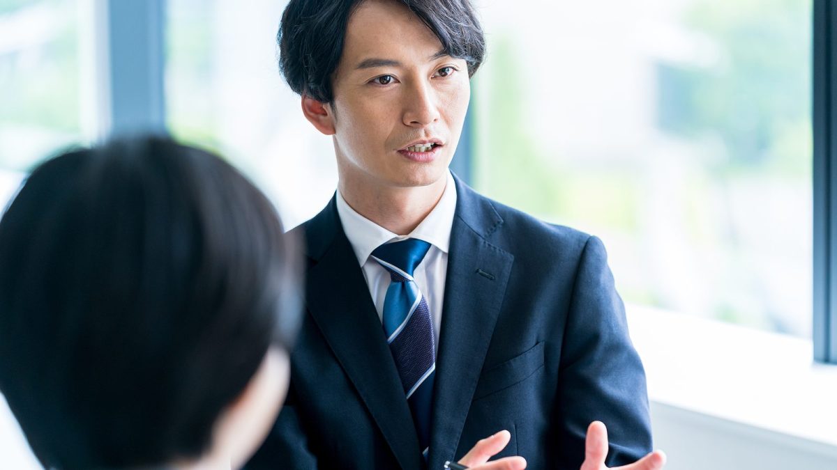 ジェスチャーをしながら話すスーツ姿の男性