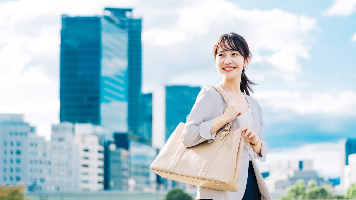 晴れの日にオフィス街を歩くスーツ姿の女性