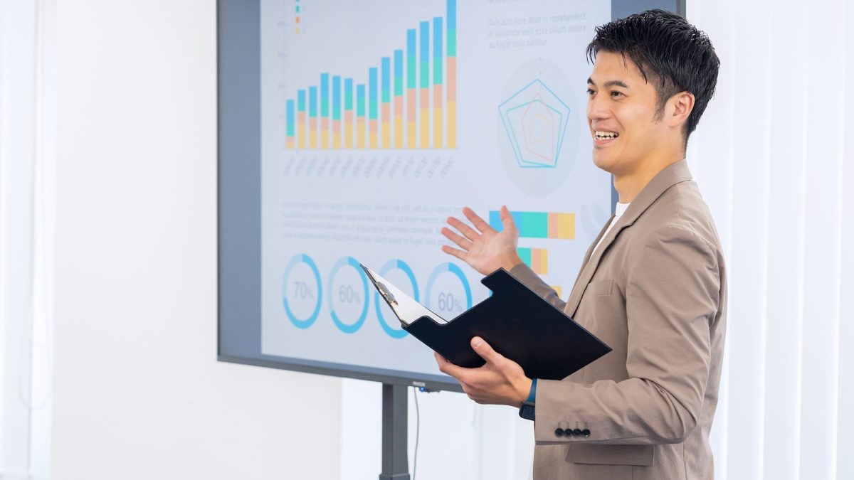 A man presenting materials projected on a large monitor