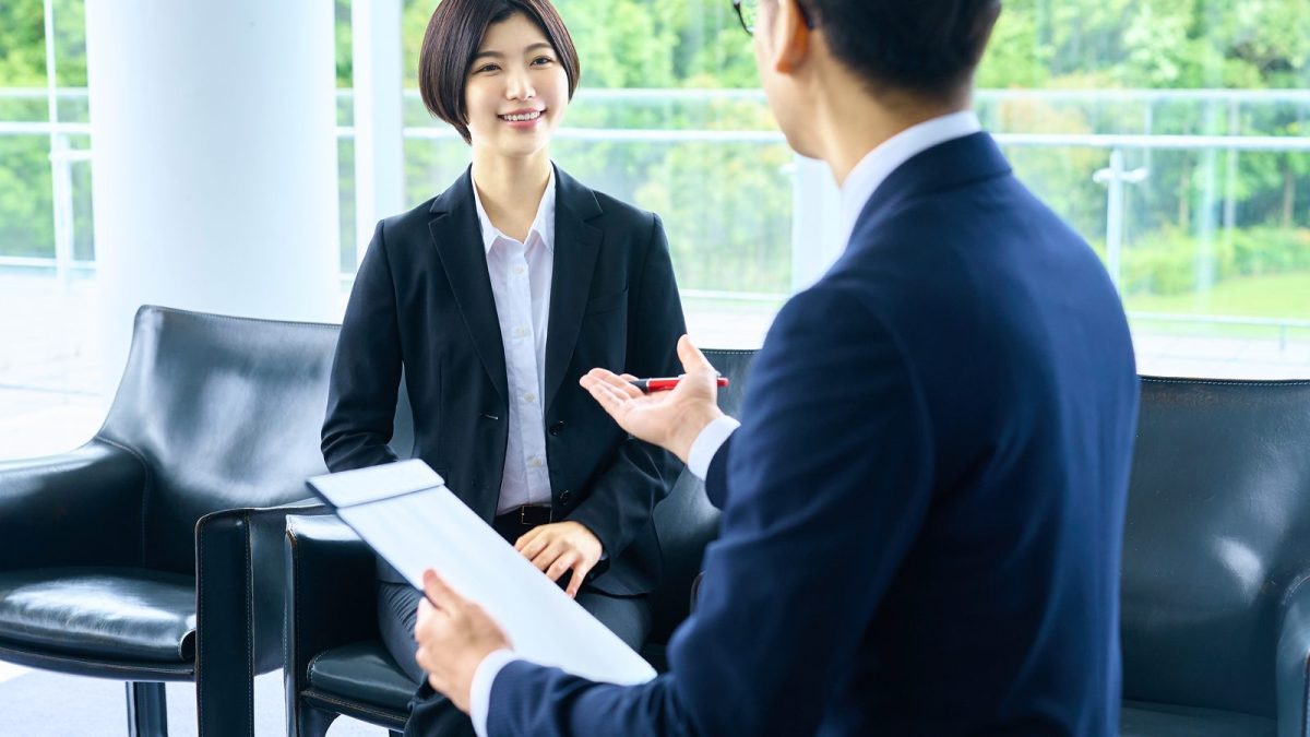 バインダーを手に持って話すスーツ姿の男性