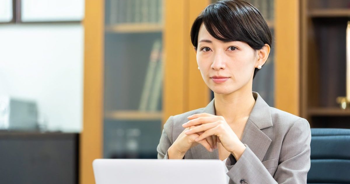 開いたノートパソコンの前で手を組む女性