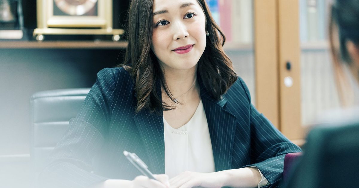 相手の話を聞きながら手書きでメモを取る女性