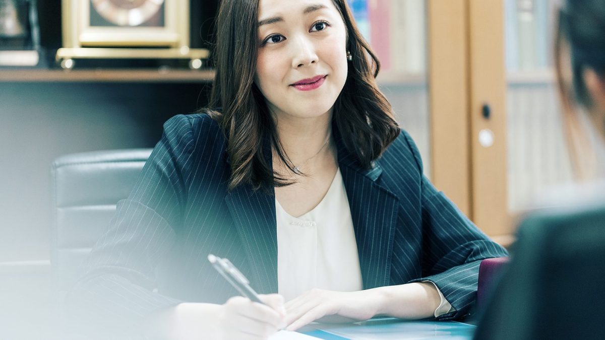 ボールペンでメモを取りながら相手の話を聞く女性