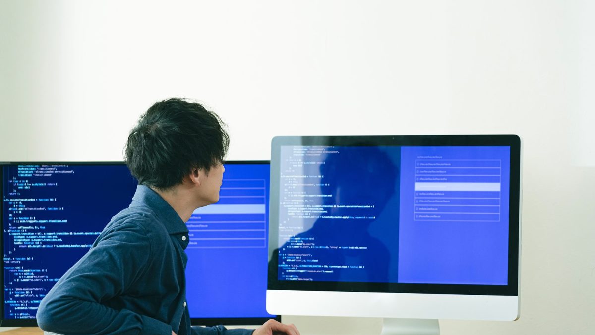 モニターに画面を映してプログラミングをする男性