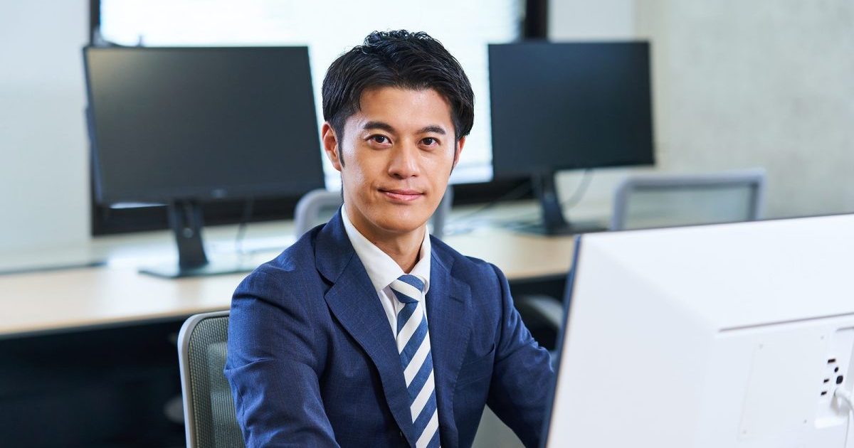オフィスの席に座るスーツ姿の男性