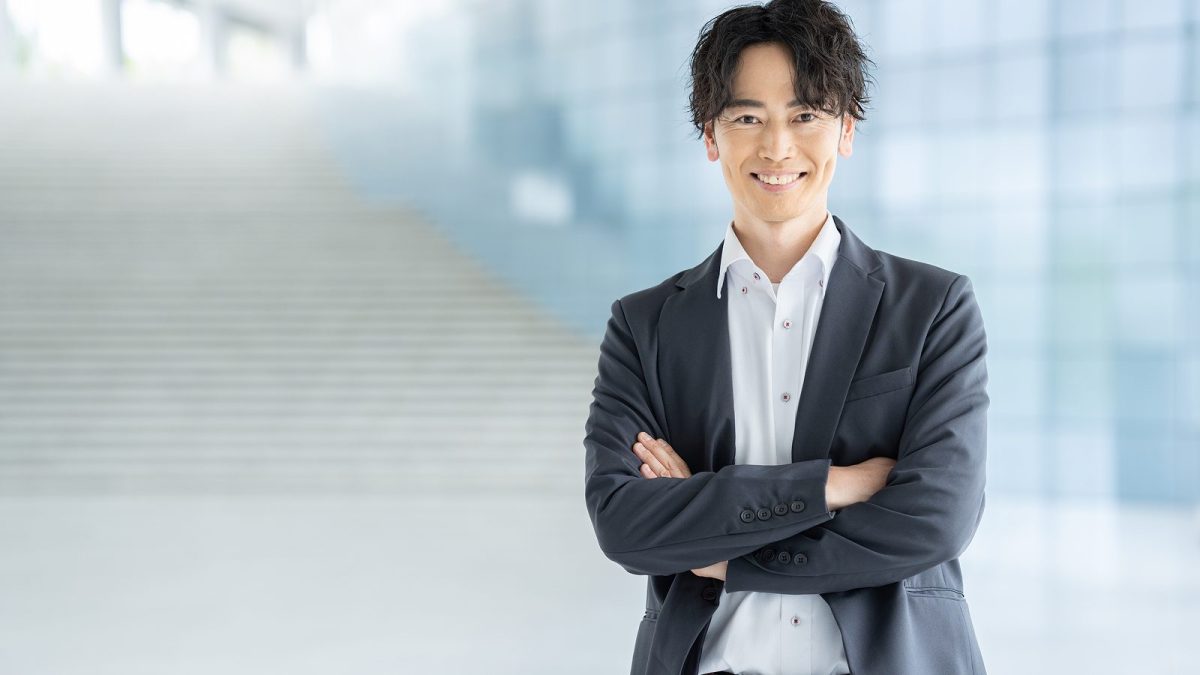 階段の前で腕を組んで立っているスーツ姿の男性