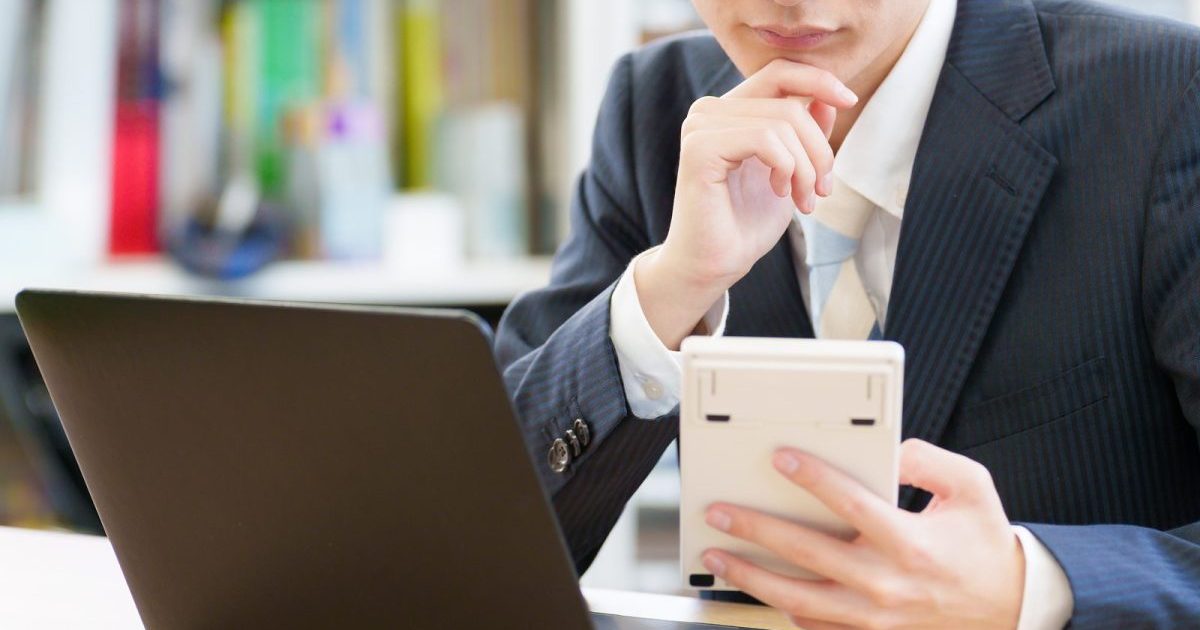 パソコンと電卓を見ながら考える様子