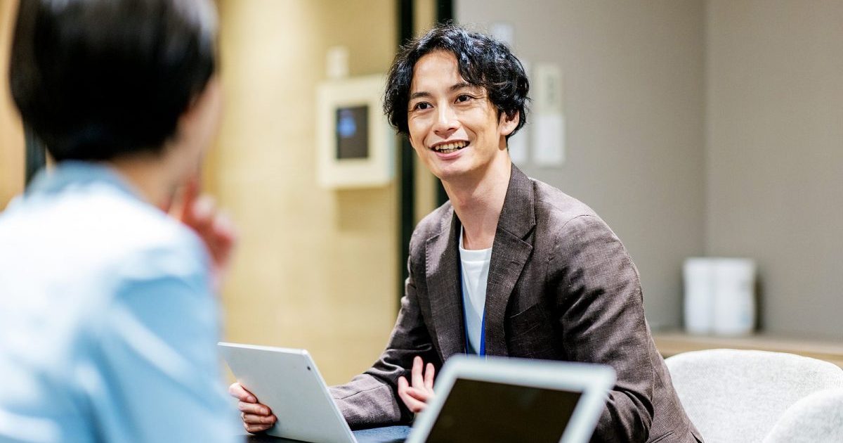 タブレットを片手に持って話す男性